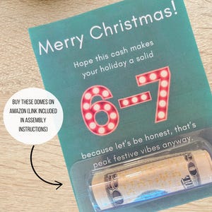 May include: A teal Christmas card with the words "Merry Christmas!" and the numbers "6-7" in red lights. A rolled-up bill is visible in a clear plastic holder. Several twenty-pound notes are visible.