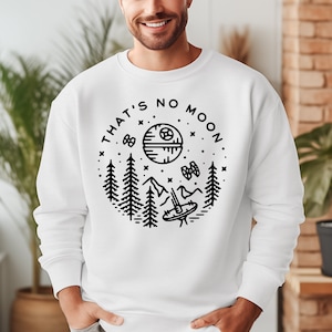 May include: White sweatshirt with a black graphic design of a Death Star with the text "That's No Moon" in a circle. The graphic also includes trees, mountains, and a TIE fighter.