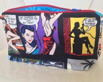 Può includere: Una pochette nera con cerniera con una stampa a fumetti colorata che presenta donne in varie pose e fumetti con testo che recita "SUSAN... IS THIS BIKINI TOO TOO REVEALING", "THAT SUNDRESS IS TOO TIGHT AND TOO LOW, BUT WOW!" e "OH YES JIM I ARRIVE TOMORROW AT NOON".