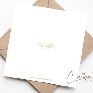 May include: A white card with the text "Courtesan Cards" in gold lettering. The card is sitting on a brown envelope.