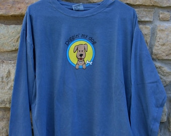 May include: A blue long-sleeved t-shirt with a cartoon dog graphic and the text "Diggin' my dog".