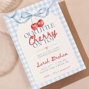 May include: Baby shower invitation with a blue gingham border and a watercolor design. The invitation features the text "Our Little Cherry on Top" in red script, along with event details and the name Sarah Graham.