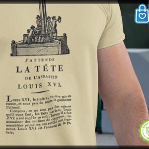 May include: Beige t-shirt featuring a black and white illustration of a guillotine and text in French. The text reads "J'attends la tête de l'assassin Louis XVI."