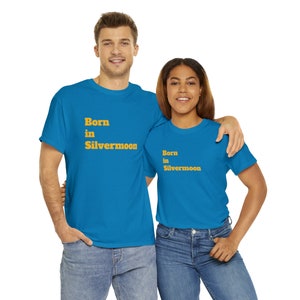 Puede incluir: Dos personas con camisetas azules a juego con el texto "Born in Silvermoon" en amarillo. Las camisetas son de un azul brillante.
