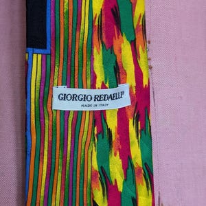May include: A colorful silk tie with a geometric pattern and a label that reads "Giorgio Redaelli" Made in Italy.