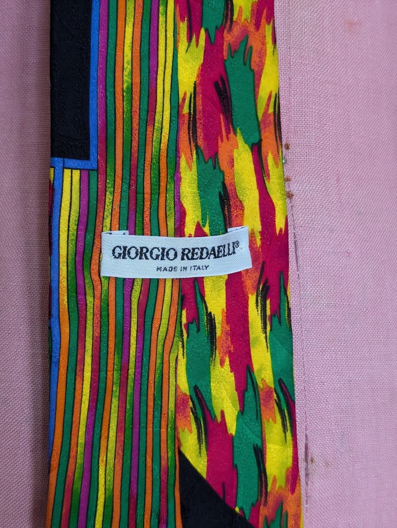 May include: A colorful silk tie with a geometric pattern and a label that reads "Giorgio Redaelli" Made in Italy.
