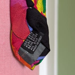 May include: A colorful silk tie with a black label that reads "100% SETA PURE SEIDE ALL SILK MADE IN ITALY".