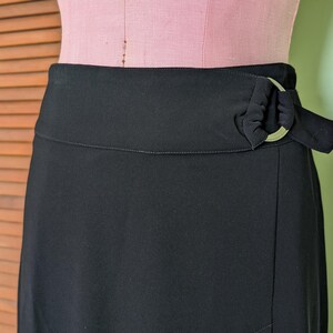 May include: A black wrap skirt with a silver ring detail at the waist.