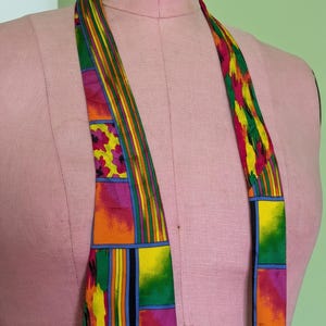 May include: A colorful silk tie with a geometric pattern in shades of orange, yellow, green, pink, and blue.