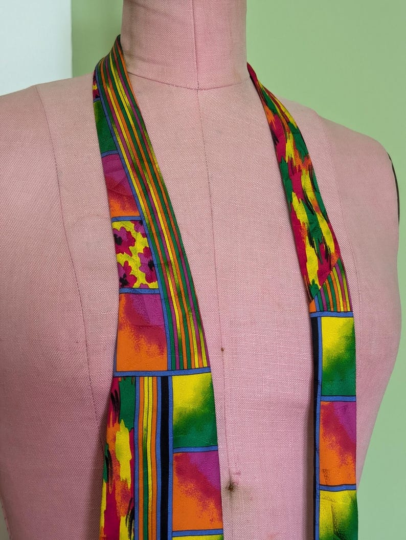 May include: A colorful silk tie with a geometric pattern in shades of orange, yellow, green, pink, and blue.