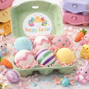 May include: An Easter-themed display featuring a green egg carton with six colorful bath bombs. The bath bombs are decorated with glitter and patterns. The carton is surrounded by decorative elements, including toy bunnies, carrots, and the words "Happy Easter".