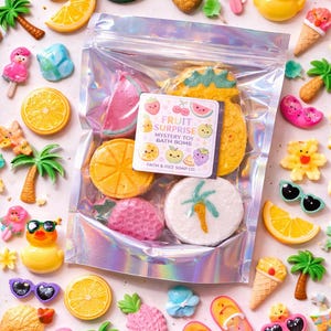 May include: A clear bag filled with colorful fruit-shaped bath bombs, including watermelon, orange, and pineapple. The bag has a label that reads "Fruit Surprise Mystery Toy Bath Bomb." Scattered around are various fruit and summer-themed novelty items.
