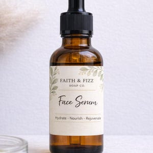 May include: A brown glass bottle of Face Serum with a black dropper. The label reads "Faith & Fizz Soap Co." and "Face Serum". The bottom of the label says "Hydrate. Nourish. Rejuvenate."