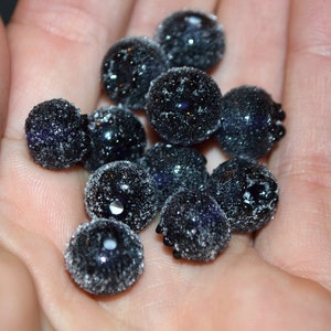 May include: A close-up of a handful of dark blue blueberries covered in a light dusting of white frost.