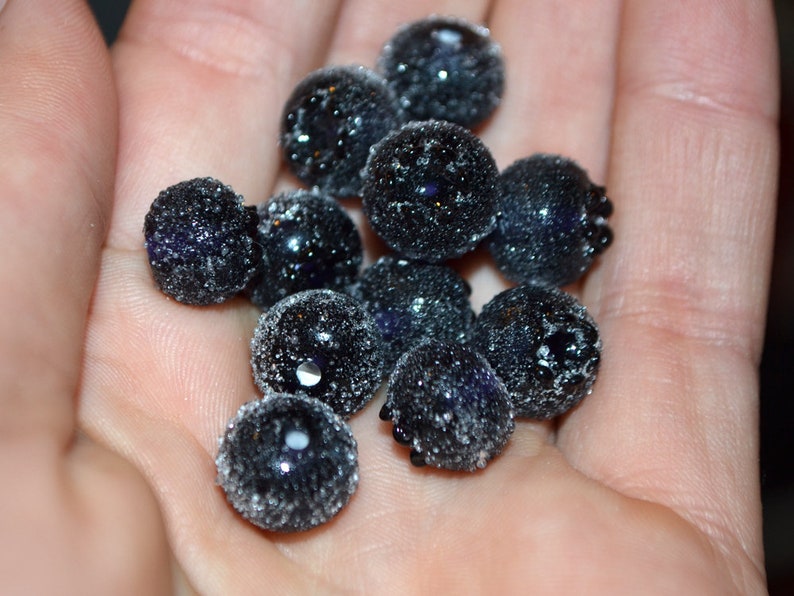 May include: A close-up of a handful of dark blue blueberries covered in a light dusting of white frost.