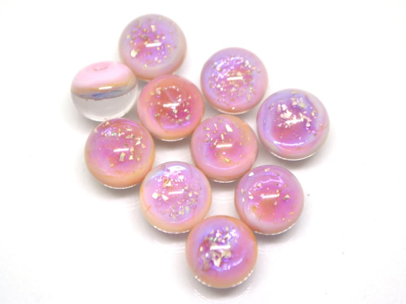 May include: Ten iridescent pink glass beads with a shimmery finish. The beads are round and have a slightly translucent appearance.