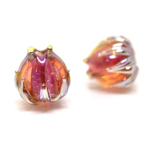 Pode incluir: Duas contas de vidro iridescentes em tons de rosa e laranja. As contas têm um design texturizado em forma de flor.