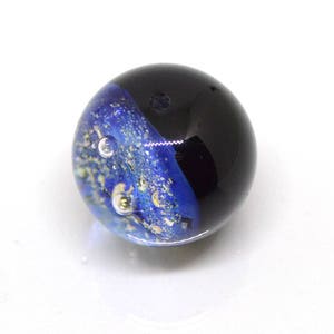 May include: A blue and black glass marble with gold flecks and air bubbles. The marble has a swirling pattern.