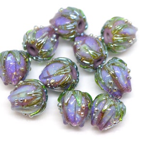 May include: A collection of ten glass beads with a purple and green iridescent finish. The beads are shaped like a flower bud and have a textured surface.
