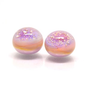 May include: Two round glass beads with a pink and purple iridescent finish. The beads have a subtle shimmer and are speckled with gold glitter.