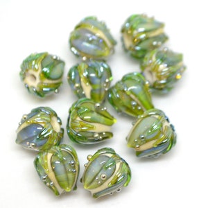 K&ouml;nnte beinhalten: Eine Sammlung von 10 gr&uuml;nen und wei&szlig;en Glasperlen mit perlmuttartigem Finish. Die Perlen sind in Form von kleinen Blumen mit einer strukturierten Oberfl&auml;che.