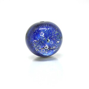May include: A blue glass bead with silver flecks and air bubbles inside. The bead has a speckled, galaxy-like appearance.