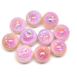 May include: Ten iridescent pink glass cabochons with gold flecks. The cabochons are round and have a smooth, glossy finish.