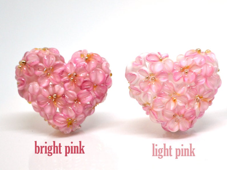 May include: Two heart-shaped arrangements of pink flowers. The flowers on the left are a bright pink, while the flowers on the right are a light pink.