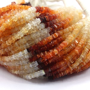 Peut inclure: Un brin de perles de pierres précieuses orange, jaune et blanche. Les perles sont de forme carrée et ont une finition facetée.