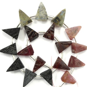 May include: A strand of triangular gemstone beads in black, red, and grey colors. The beads are strung on silver wire.