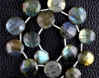 May include: A strand of faceted, round labradorite beads. The beads display a mix of gray, blue, and green hues, with a shimmering, iridescent quality. The beads are strung on a silver-colored wire.