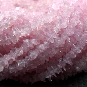 May include: A strand of pink rose quartz chips, with a smooth, polished finish. The chips are irregular in shape and size, and have a translucent appearance.