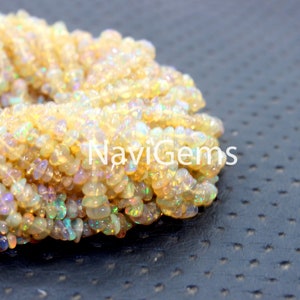 May include: A strand of iridescent white opal chip beads. The beads are small and irregular in shape, with a slightly translucent appearance. The beads are strung together on a clear thread.