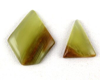 May include: Two green and brown gemstone cabochons, one is a diamond shape and the other is a triangle shape.