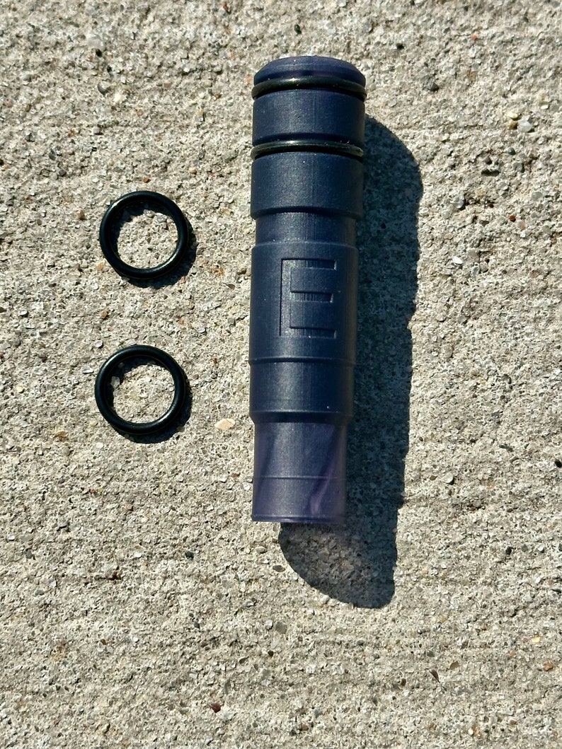 May include: A dark blue plastic tube with black rings and two black rubber o-rings.