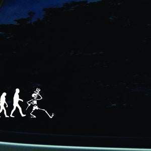 May include: A white vinyl sticker depicting the evolution of man, ending with a skeleton wearing a top hat and holding a cane.