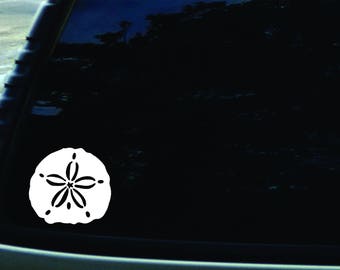 May include: White vinyl decal of a sand dollar on a black car window.