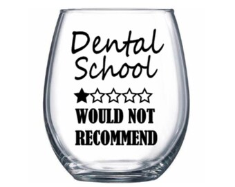 May include: A clear glass wine glass with a black vinyl decal that reads "Dental School - Would Not Recommend" with a one-star rating.