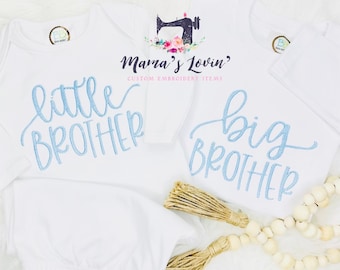 May include: Two white baby onesies with blue embroidery. One onesie says "little brother" and the other says "big brother".
