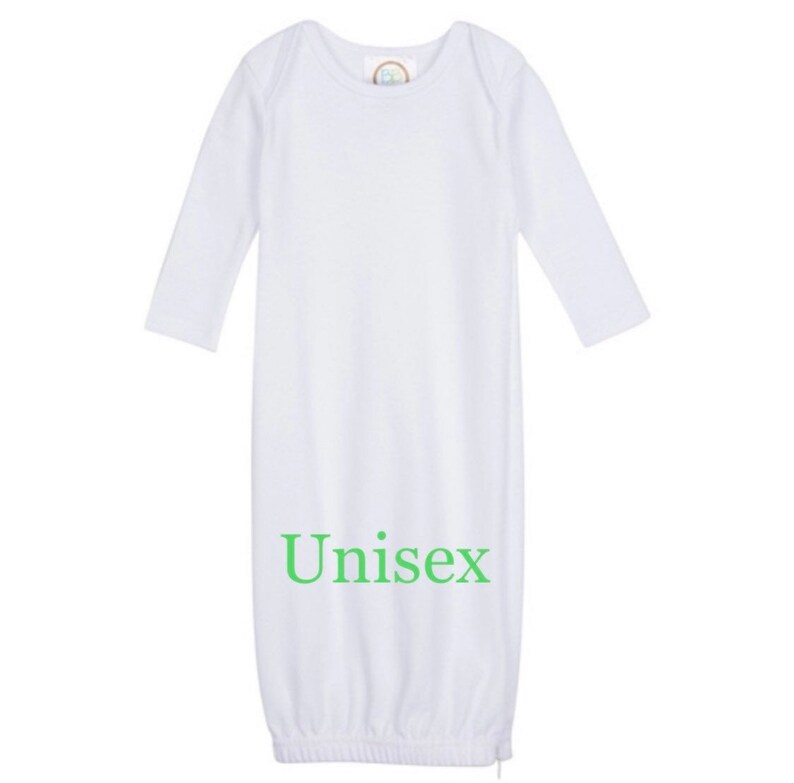 Puede incluir: Batista blanca de manga larga con cuello vuelto y parte inferior fruncida. La bata tiene la palabra "Unisex" impresa en verde en la parte delantera.