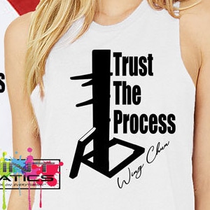 Könnte beinhalten: Zwei Personen tragen weiße T-Shirts mit einer schwarzen Silhouette einer Wing Chun-Puppe und dem Text "Trust The Process Wing Chun". Die Person links trägt ein rot-weißes Baseball-Shirt. Die Person rechts trägt ein weißes Tanktop.