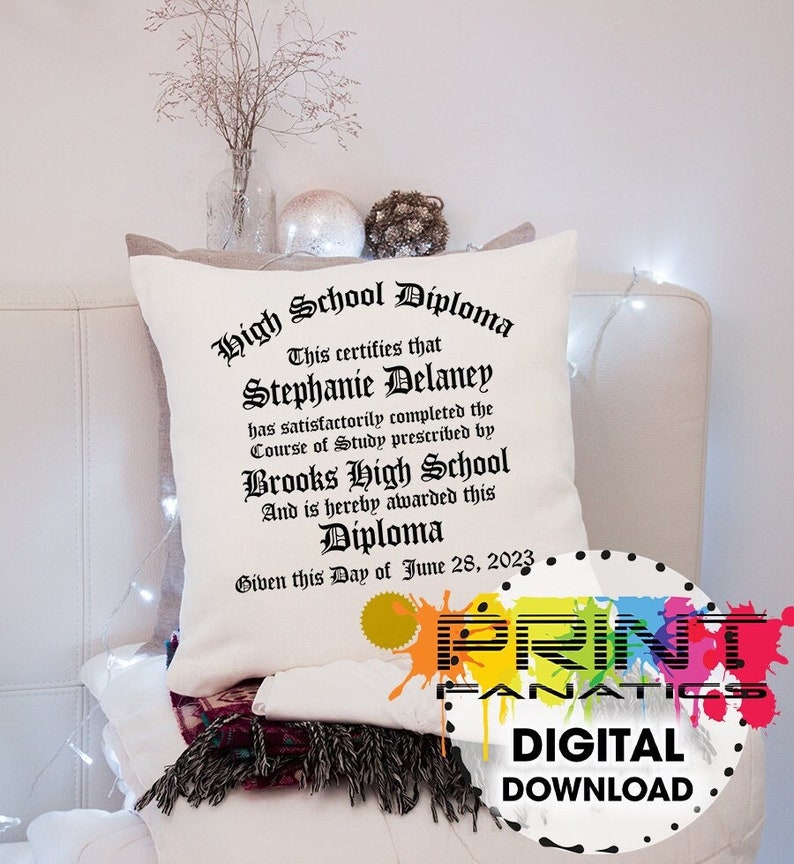 Puede incluir: Coj&iacute;n decorativo color crema con un dise&ntilde;o de diploma de escuela secundaria impreso. El texto del diploma incluye un nombre, una escuela y una fecha. El coj&iacute;n est&aacute; sobre una superficie blanca, con elementos decorativos en el fondo. Tambi&eacute;n se ven las palabras "DIGITAL DOWNLOAD".