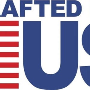 Puede incluir: La imagen muestra el texto "HANDCRAFTED IN THE USA" en azul oscuro. A la izquierda, la bandera estadounidense con rayas rojas y blancas y un campo azul con estrellas blancas. El texto indica el origen del producto.