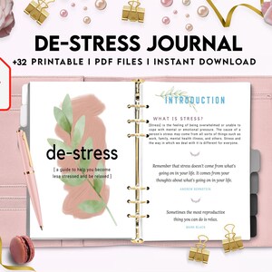 May include: A pink and white journal with the title "De-Stress Journal" and the text "+32 Printable I PDF Files I Instant Download". The journal has a green leaf design and the words "de-stress" in a pink and white font. The journal is open to a page with the title "Introduction" and the text "What is Stress?" and "Remember that stress doesn't come from what's going on in your life. It comes from your thoughts about what's going on in your life."