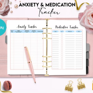 May include: A pink and white planner with two pages visible. The left page is titled "Anxiety Tracker" and has columns for date and time, trigger, symptoms, outcome, and anxiety rating. The right page is titled "Medication Tracker" and has columns for date, medicine, and time. There are checkboxes next to each medicine entry.