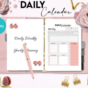 May include: A pink and gold daily planner with the text "DAILY Calendar" and "Monday" on the cover. The planner has sections for priorities, errands, to do list, to remember, and notes.