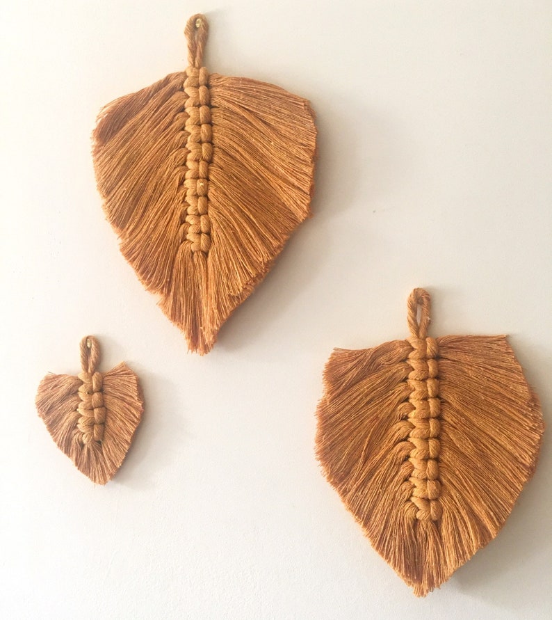 Puede incluir: Tres tapices de macram&eacute; en forma de hojas, hechos con un cord&oacute;n marr&oacute;n natural. La hoja m&aacute;s grande est&aacute; en la parte superior, y la hoja m&aacute;s peque&ntilde;a est&aacute; en la parte inferior.