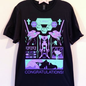 Puede incluir: Camiseta negra con un estampado gr&aacute;fico morado y verde de un robot con el texto "CONGRATULATIONS!" y "WARNING" en el dise&ntilde;o.