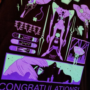 Puede incluir: Una camiseta negra con un dise&ntilde;o gr&aacute;fico verde ne&oacute;n y morado. El dise&ntilde;o presenta un robot, una criatura y una ciudad. El texto "CONGRATULATIONS!" est&aacute; impreso en morado en la parte inferior de la camiseta.