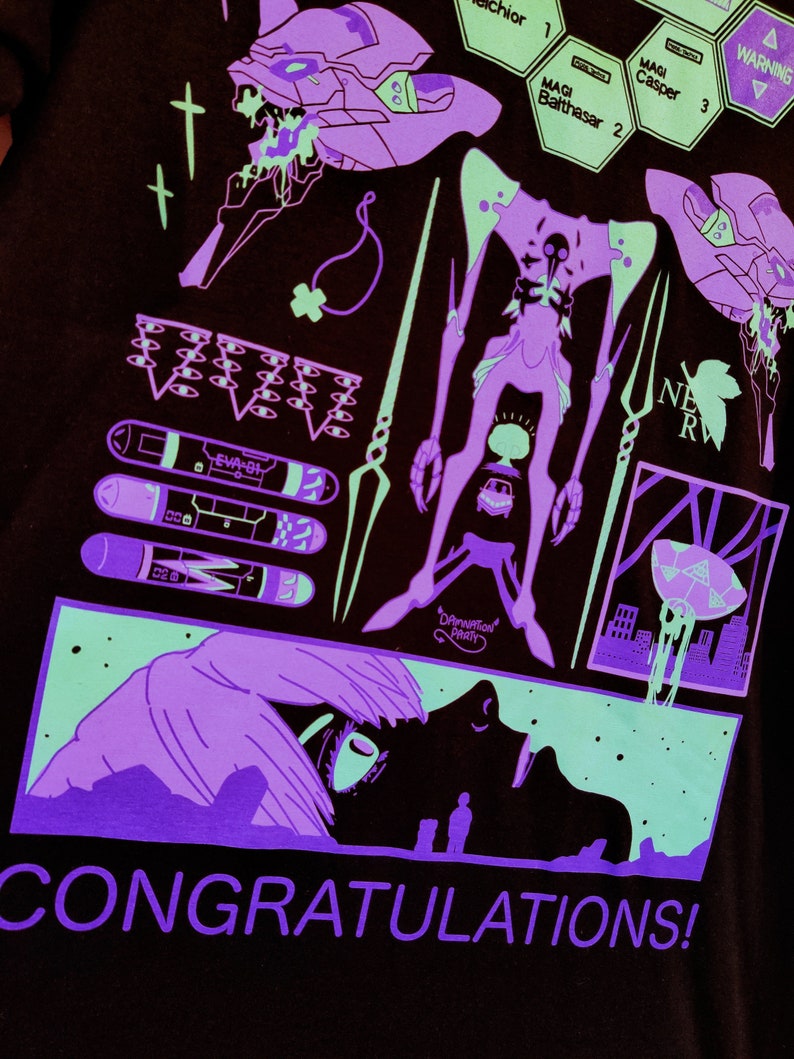 Puede incluir: Una camiseta negra con un dise&ntilde;o gr&aacute;fico verde ne&oacute;n y morado. El dise&ntilde;o presenta un robot, una criatura y una ciudad. El texto "CONGRATULATIONS!" est&aacute; impreso en morado en la parte inferior de la camiseta.